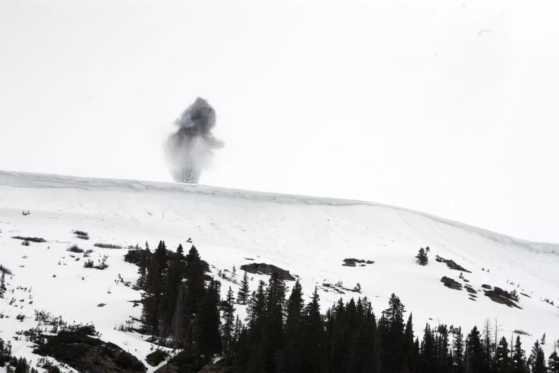 Photograph of a charge detonating high on a snowy slope in Colorado