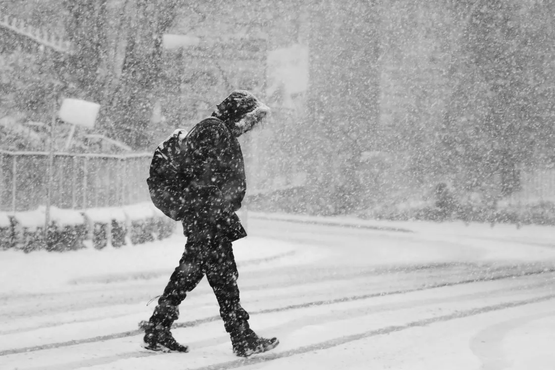 A person crosses the street during a blizzard.