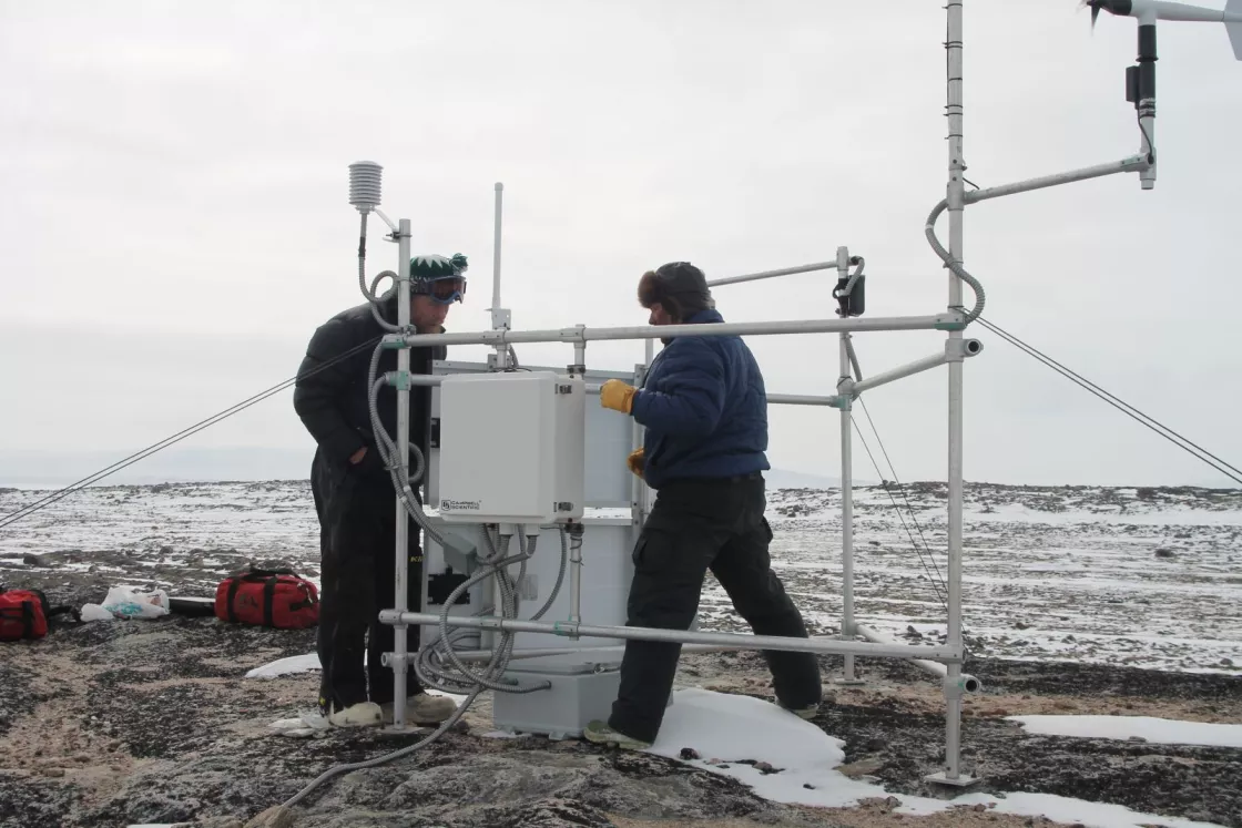 Esa Qillaq (right) and Kelly Elder check out the Ailaktalik weather station during annual maintenance. 