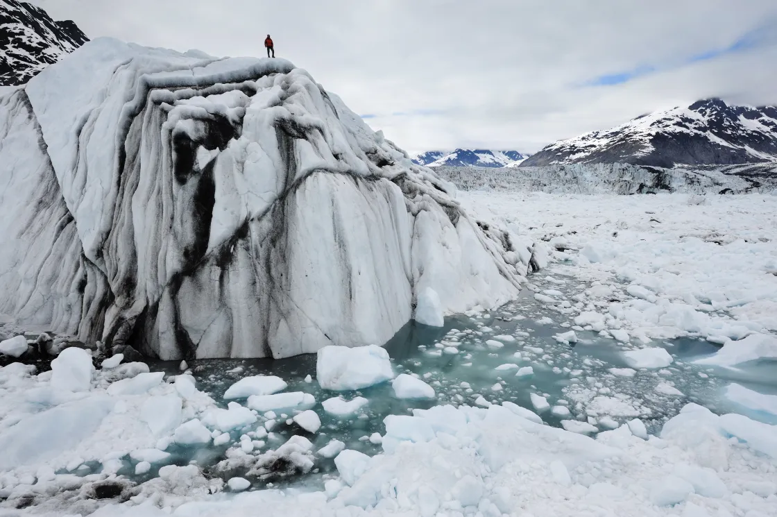 An Extreme Ice Survey team member stands atop an iceberg calved from Columbia Glacier in Alaska.