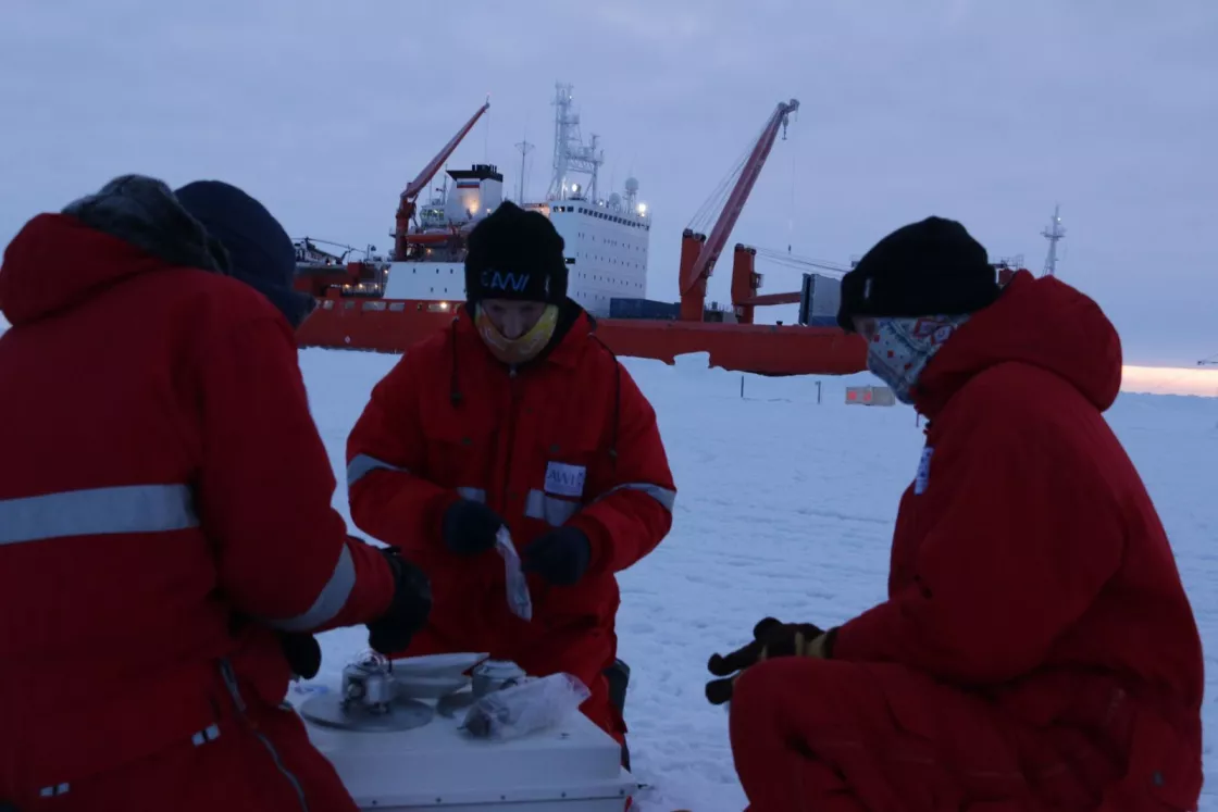 MOSAiC School participants set up a radiometer on the sea ice. Radiometers were used to calibrate the sensors on each of the three meteorological stations. From left to right: Alex Mavrovic, Sean Horvath, and Tatiana Matveeva. 