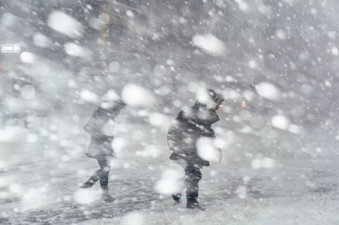 pedestrians walk through a blizzard