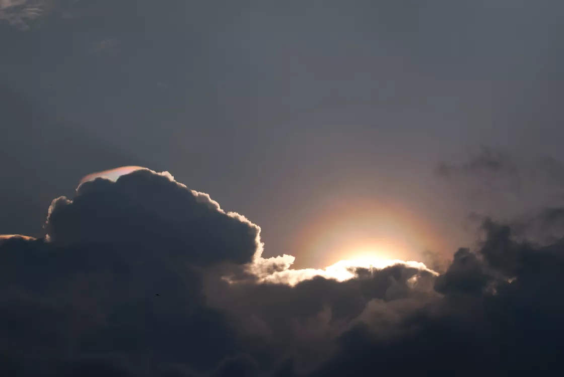 A partial solar corona is visible behind clouds