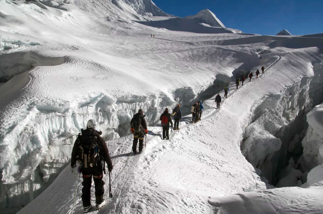 Hikers trek up to Island Peak in the Himalaya with steep crevasses to either side