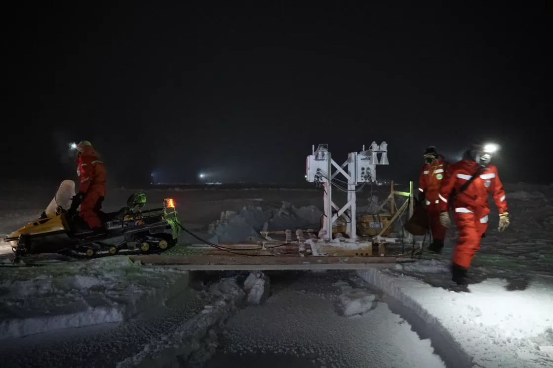 Scientists cross instruments over a lead in the Arctic Sea Ice
