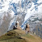 Photo of old church on summit with taller mountains in background